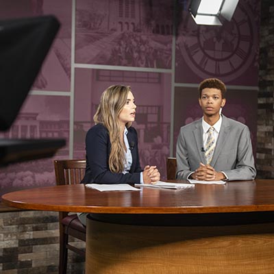 Students at the anchor desk in the TV Studio.
